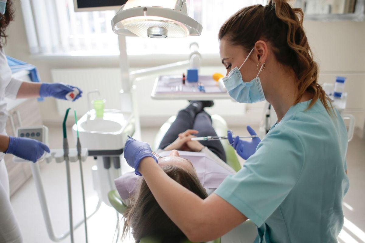 Infirmière administrant une injection à une patiente dans un cabinet dentaire Infirmière administrant une injection à une patiente dans un cabinet dentaire