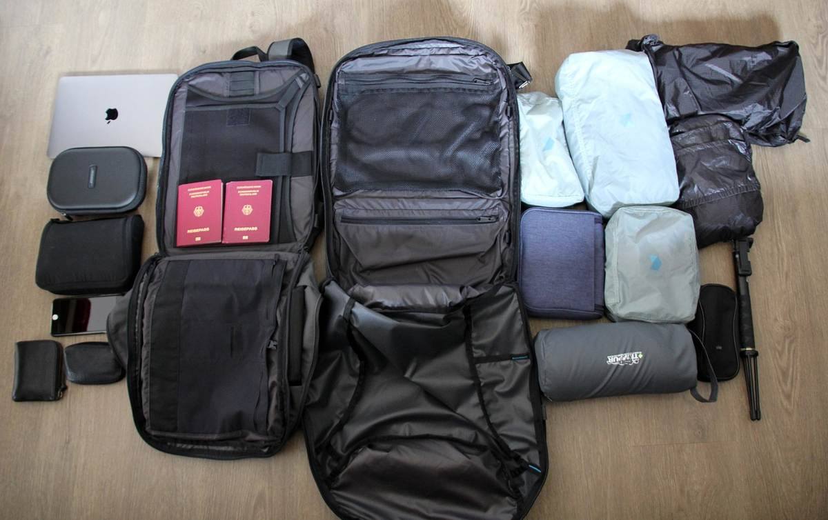 Sac à dos de voyage ouvert avec vêtements, câbles et accessoires soigneusement rangés Sac à dos de voyage ouvert avec vêtements, câbles et accessoires soigneusement rangés