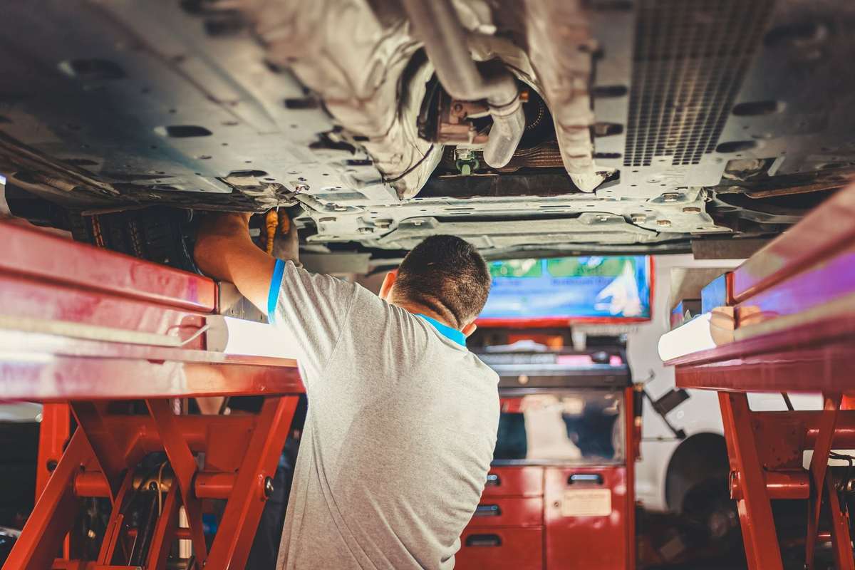 Mécanicien inspectant le dessous d'un véhicule soulevé dans un garage équipé