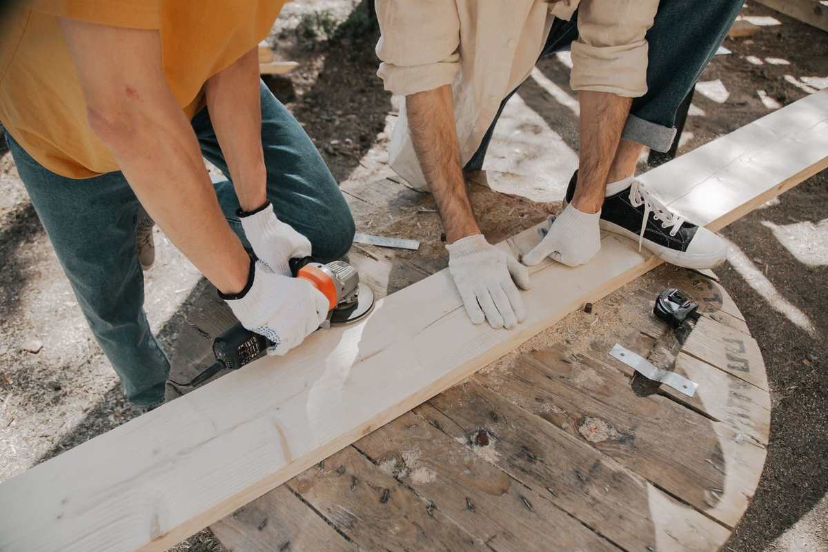 Deux hommes sciant une planche blanche sur un établi en bois Deux hommes sciant une planche blanche sur un établi en bois