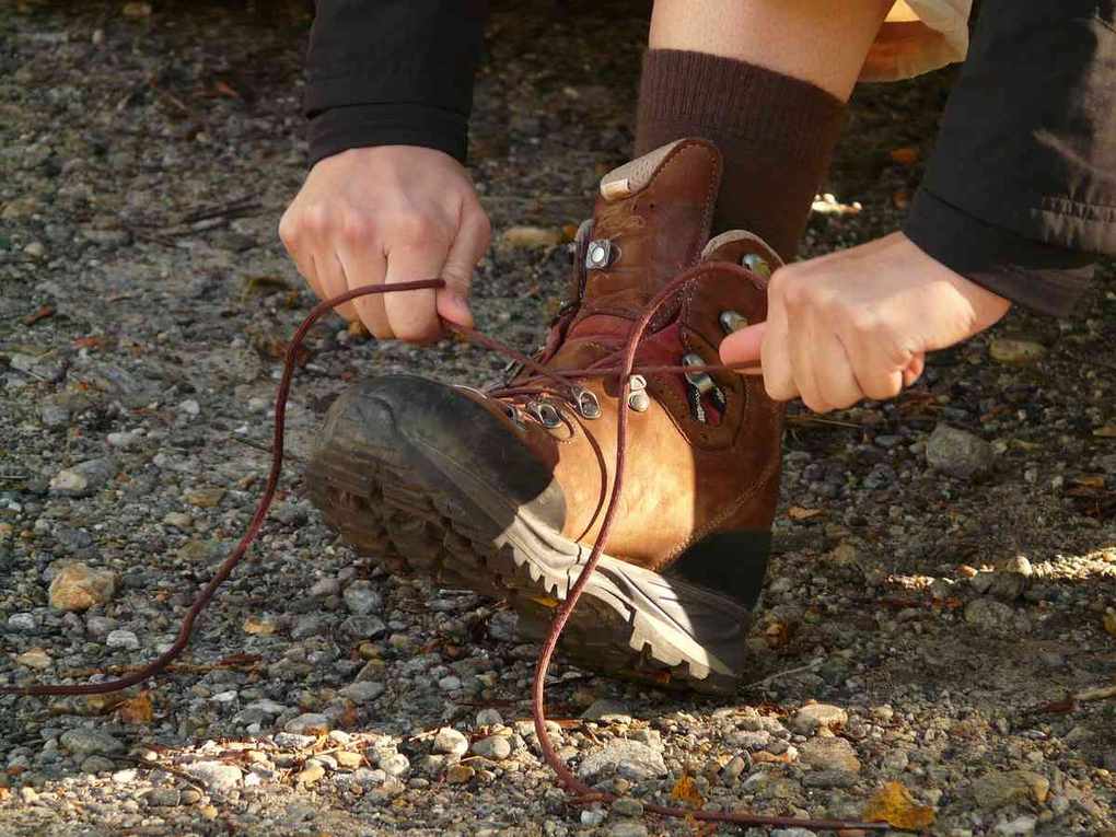 Person nouant lacets de bottes de randonnée sur un terrain rocheux Person nouant lacets de bottes de randonnée sur un terrain rocheux