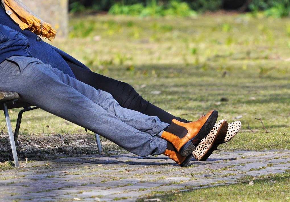 Deux personnes assises sur un banc, pieds nus, en extérieur, sur une surface pavée