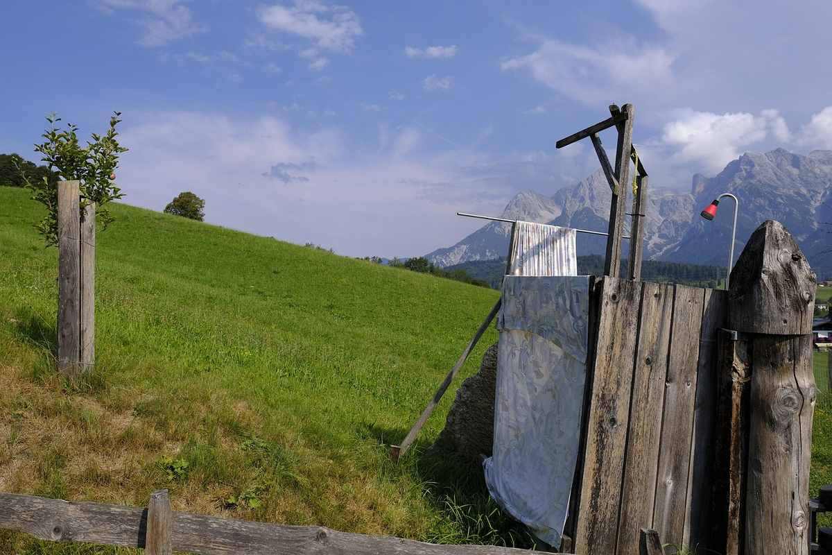 Grange en bois sur colline, fil à linge, ciel bleu, montagnes lointaines