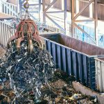 grue soulève tas de métaux dans hall d'usine