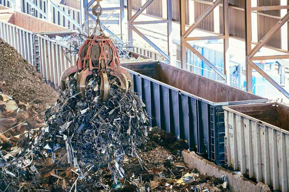 grue soulève tas de métaux dans hall d'usine