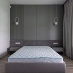 Un lit avec matelas sur cadre gris, murs et rideaux dans chambre