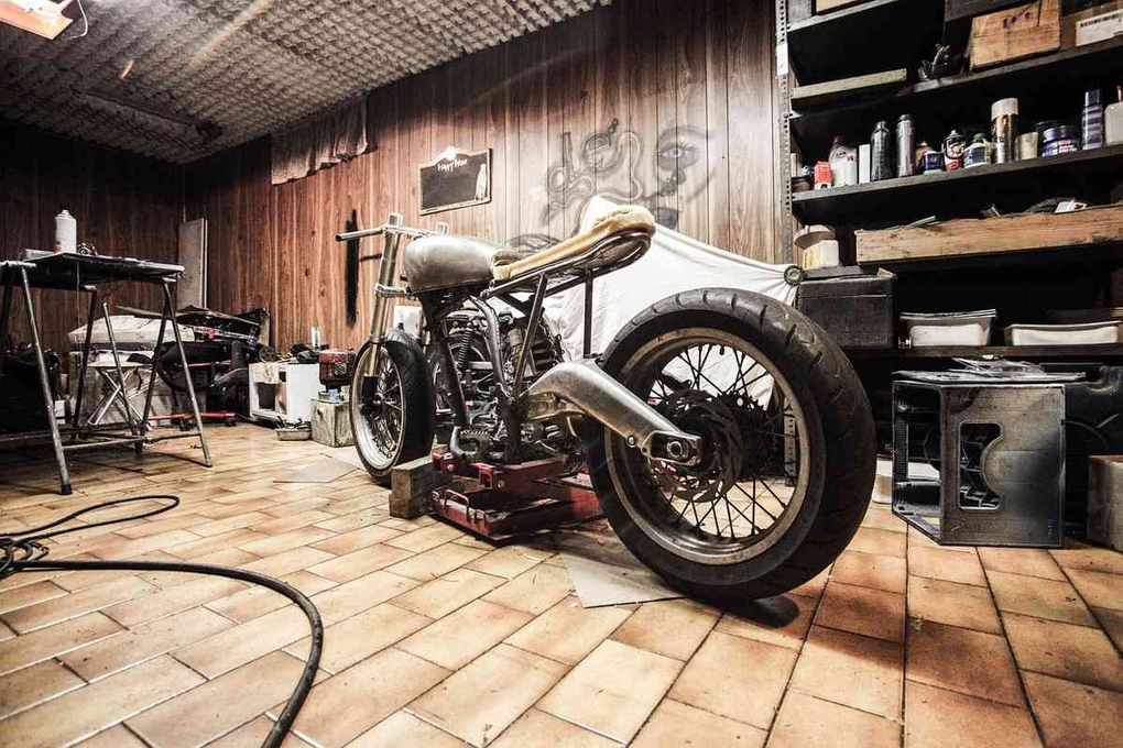 Moto en réparation dans un garage avec outils et étagères Moto en réparation dans un garage avec outils et étagères