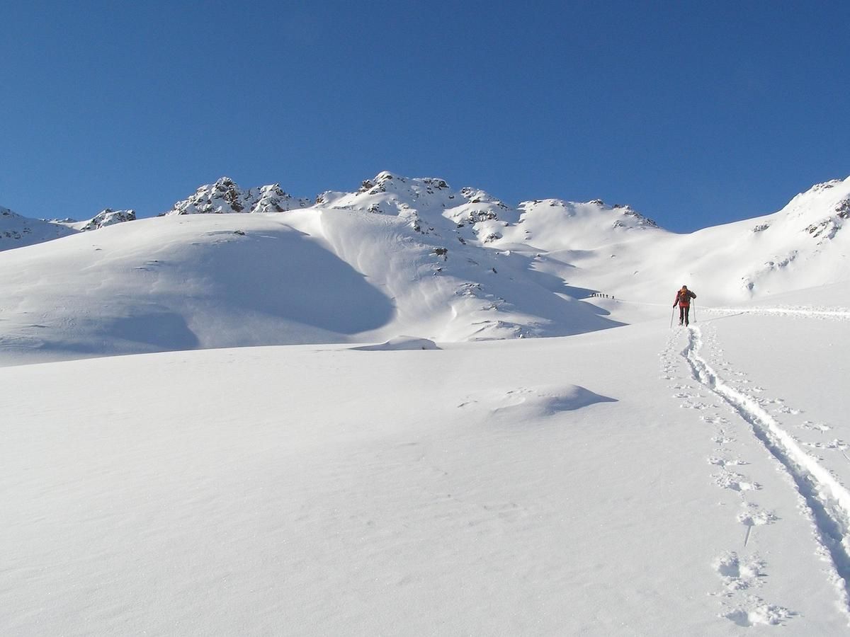 Personne marchant dans un champ enneigé avec des montagnes et un ciel bleu Personne marchant dans un champ enneigé avec des montagnes et un ciel bleu