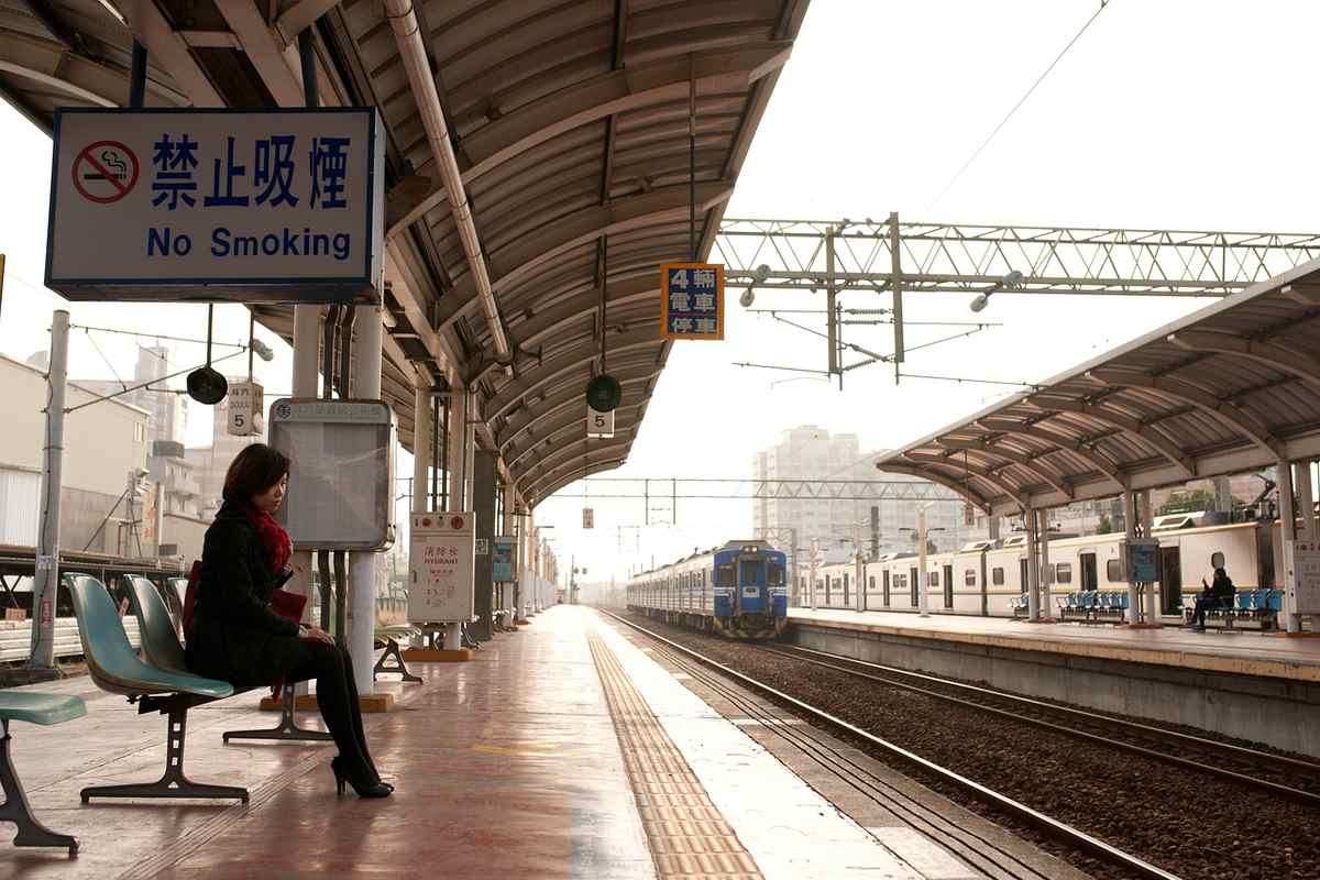 Une femme attend sur le quai de la gare, un train s'approche Une femme attend sur le quai de la gare, un train s'approche
