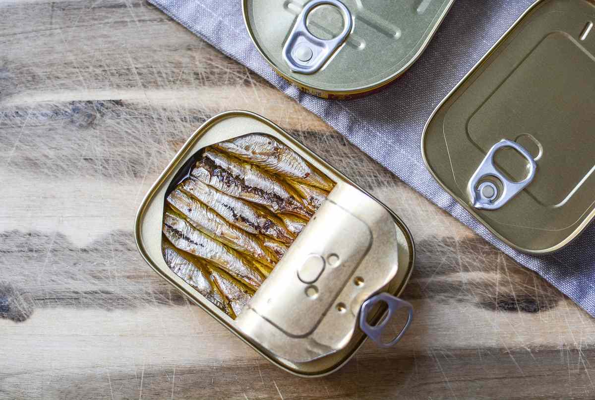 Boîte ouverte contenant des sardines sur une planche en bois