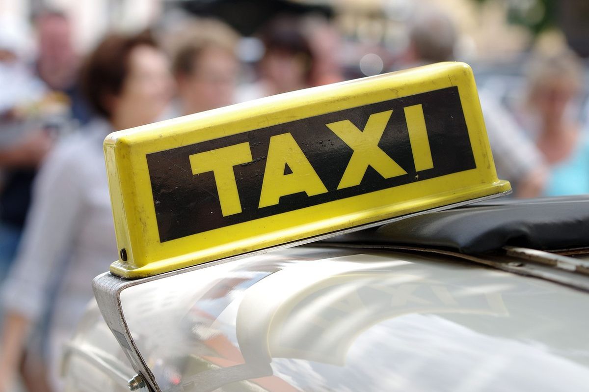 Un phare taxi jaune sur le toit d'une voiture, piétons flous en arrière-plan Un phare taxi jaune sur le toit d'une voiture, piétons flous en arrière-plan