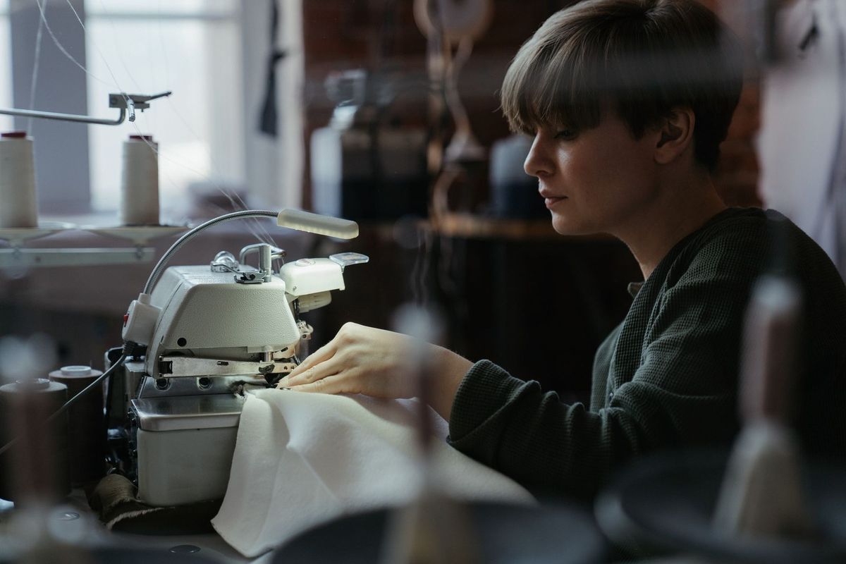 Femme utilisant une machine à coudre dans un atelier lumineux Femme utilisant une machine à coudre dans un atelier lumineux