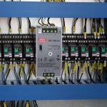 Un panneau électrique avec disjoncteurs, câbles et un régulateur